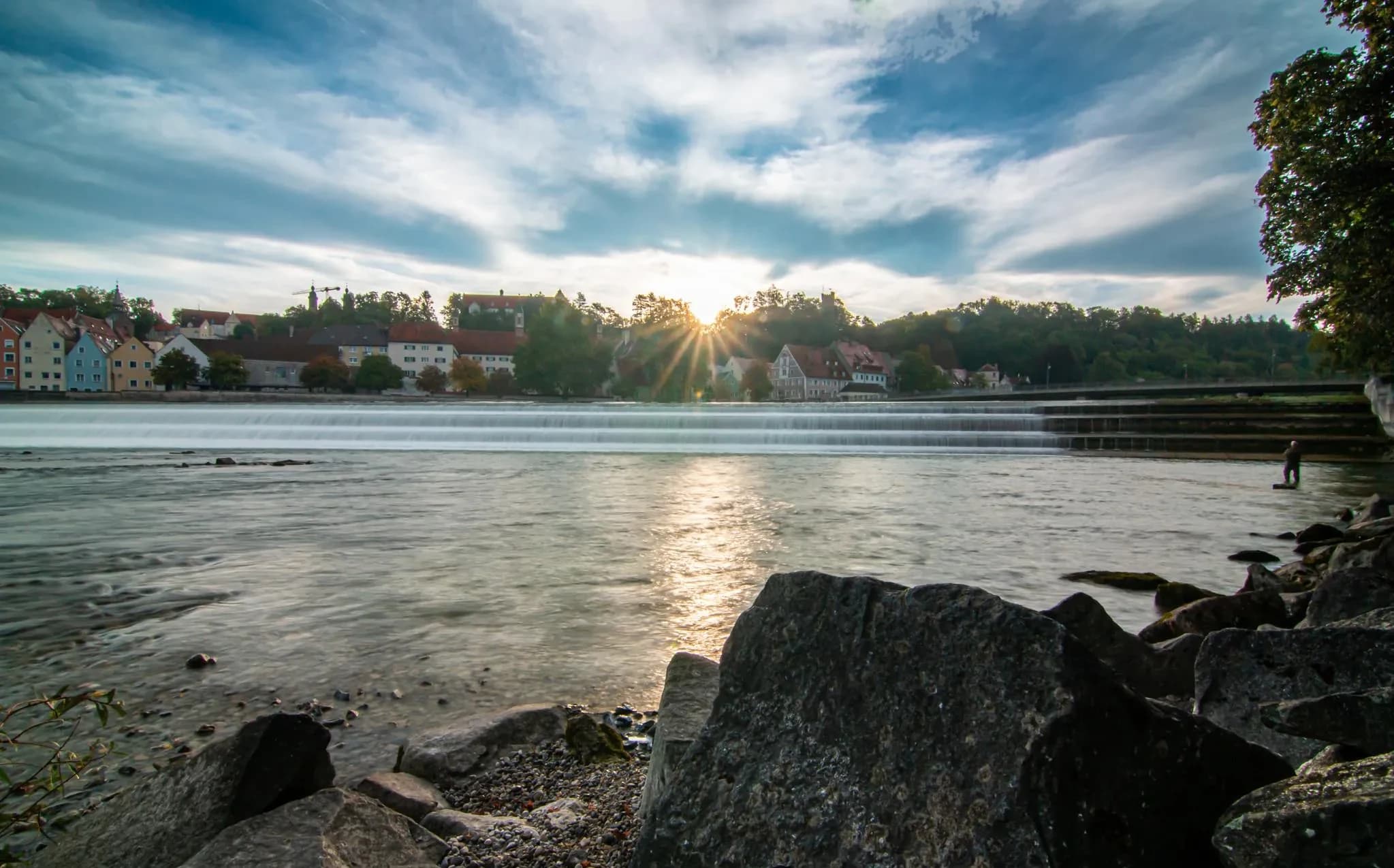 Das Lechufer in Landsberg im Gegenlicht, dahinter die Häuser der Altstadt