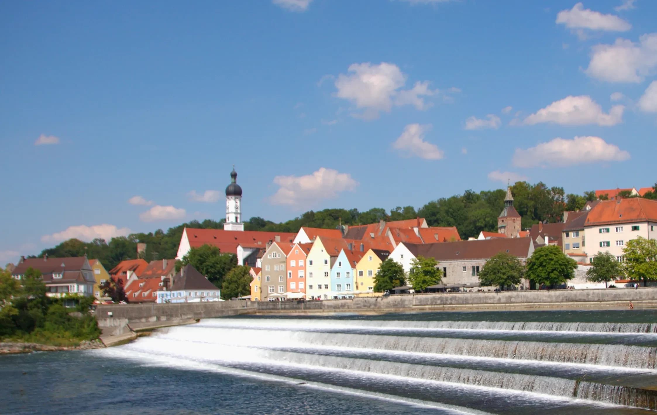 Das Lechwehr in Landsberg am Lech, dahinter die bunte Häuserzeile der Altstadt